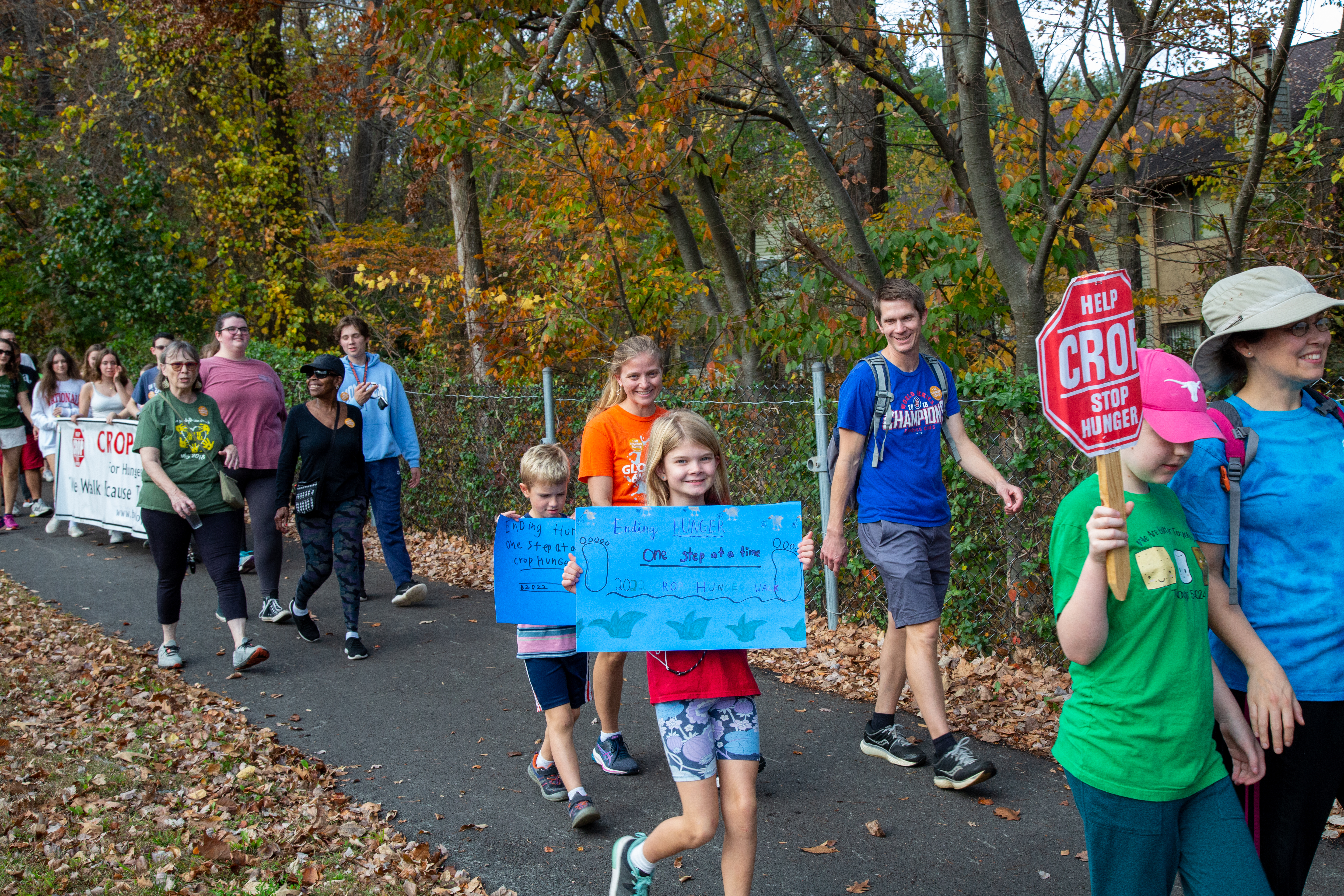 A little girl holding a sign that says 'Ending Hunger one step at a time.'